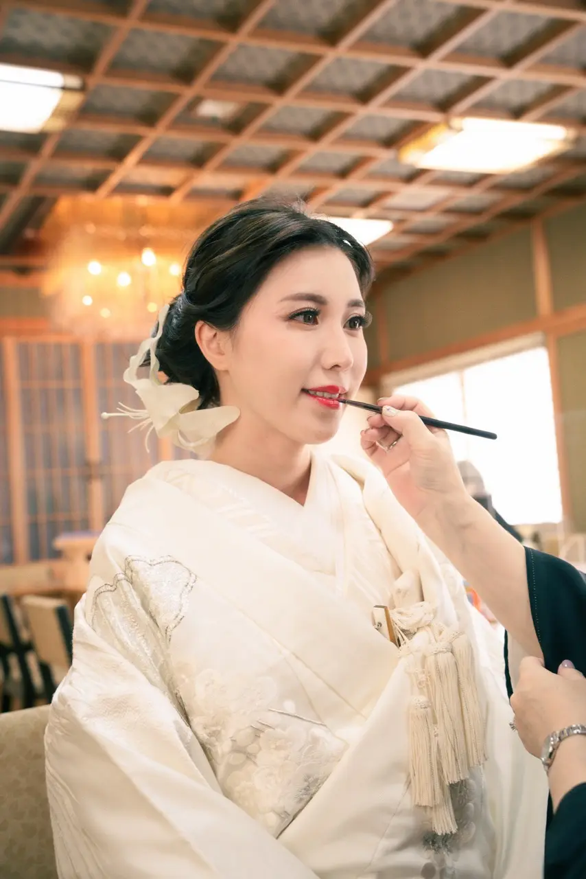 shiromuku-hairmake-style-02.webp01 Jolie万梨恵の着付けとヘアメイクです。上品なシニヨンに純白のユリの髪飾り、横顔を美しく見せるブライダルヘア、華やかなブライダルメイクです。