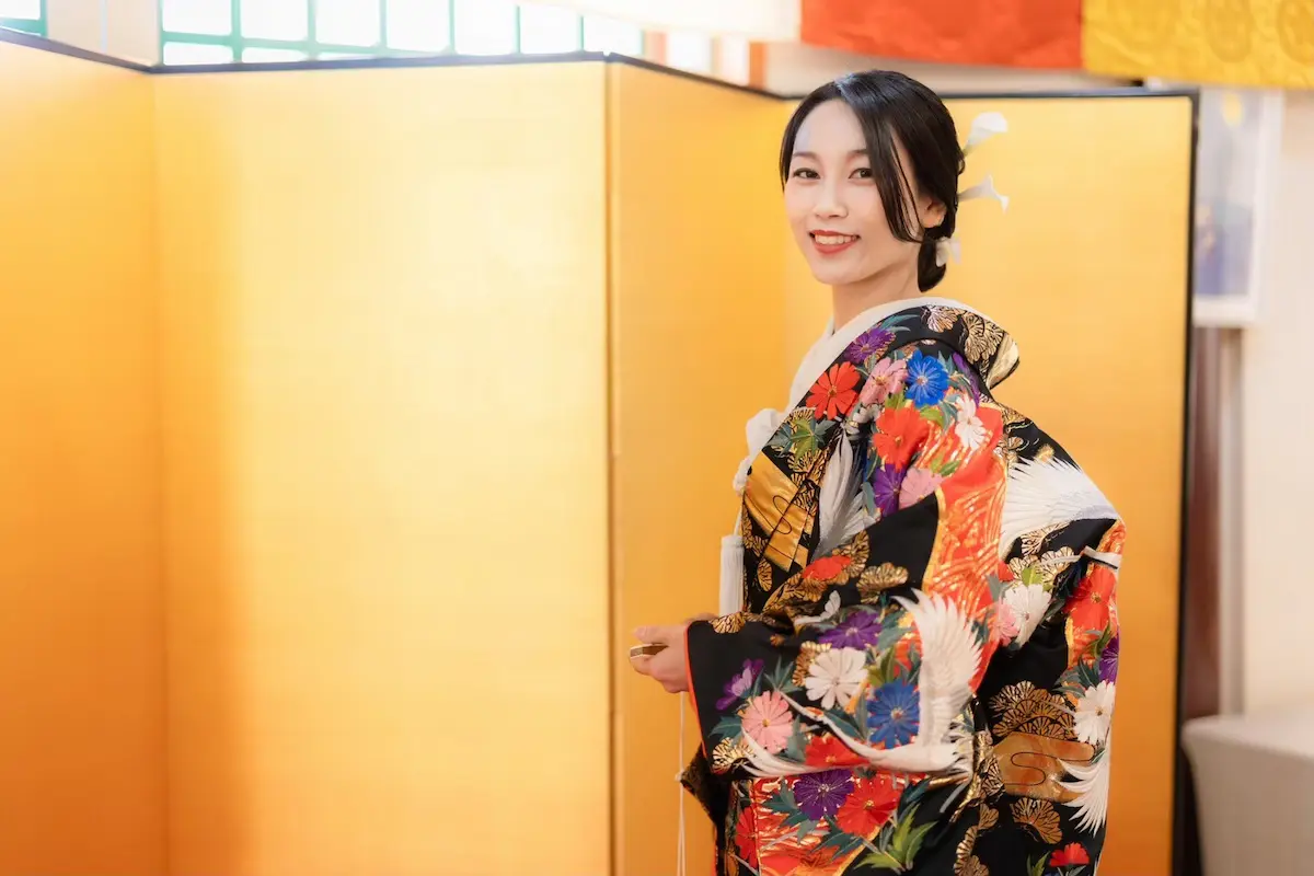 traditional-wedding-hair-06.webp01 Jolie万梨恵の着付けとヘアメイクで、豪華な金箔に鶴の刺繍が施された人気の黒打掛 高級婚礼衣装、艶やかな黒髪をシンプルなシニヨンにしました。